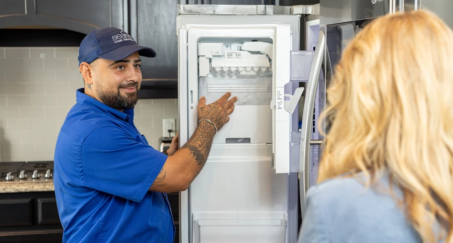 A technician performs maintenance on a kitchen refrigerator as part of a plan to save energy and money during the holidays.