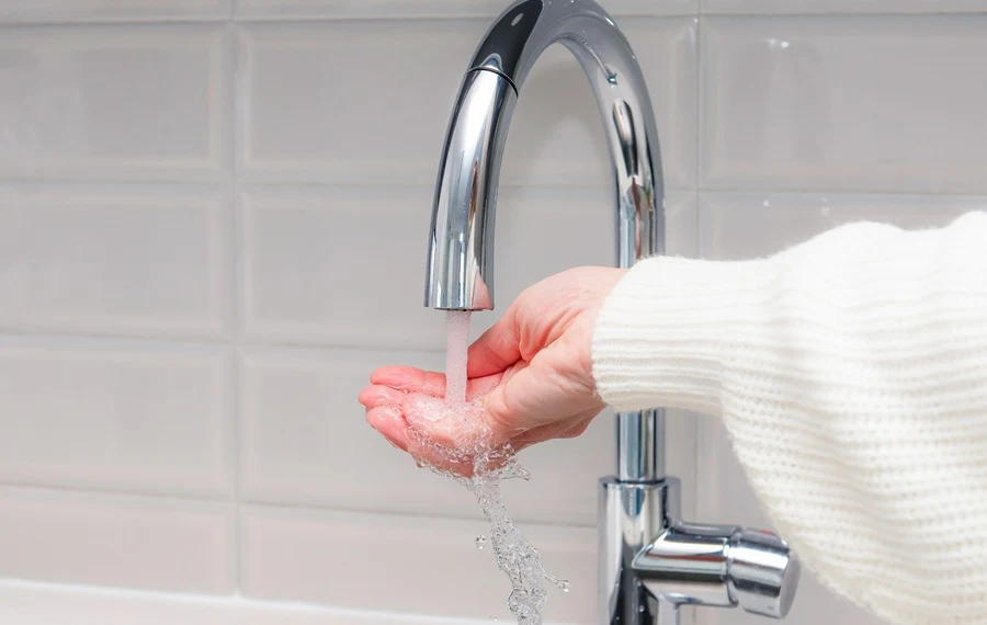 Homeowner checking water temperature and finding no hot water at the kitchen sink.