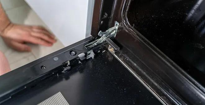 Image of homeowner examining the oven door hinge