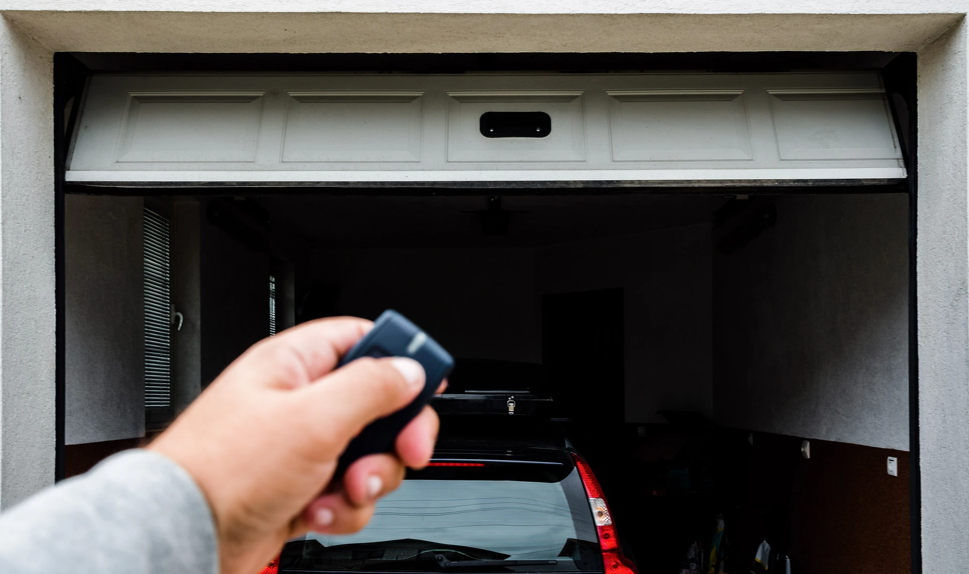 homeowner using a garage door opener remote and wondering how a garage door sensor works