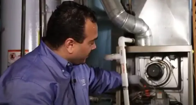 Sears Home Services technician Lenny Arroyo performing professional HVAC maintenance on a gas furnace.