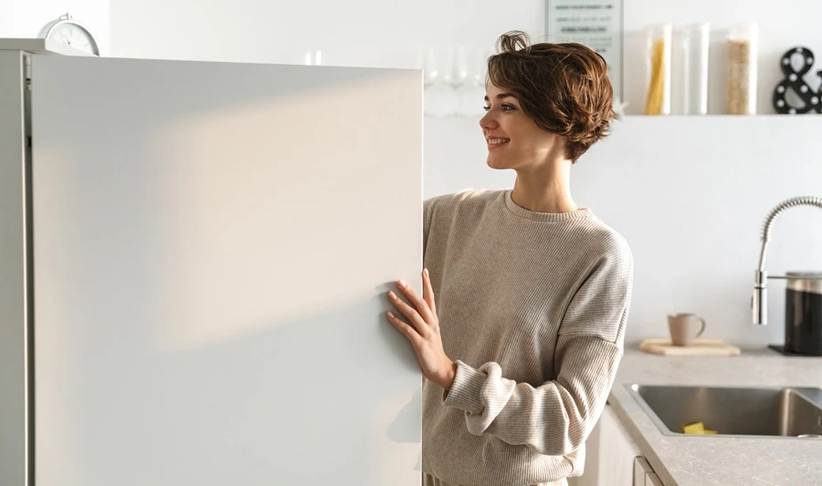 Woman retrieving food from the deep freezer and wondering about the ideal deep freezer temperature setting.