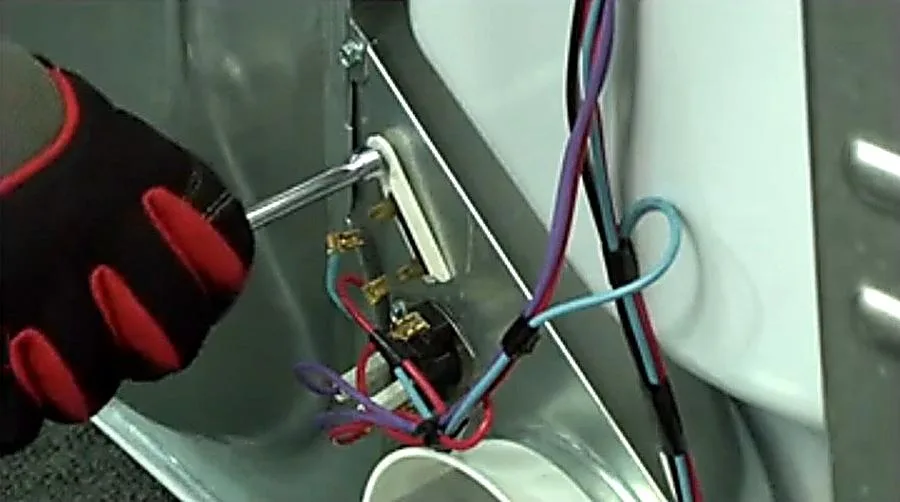 Technician replacing thermal fuse in dryer blower housing to fix dryer not starting or not heating