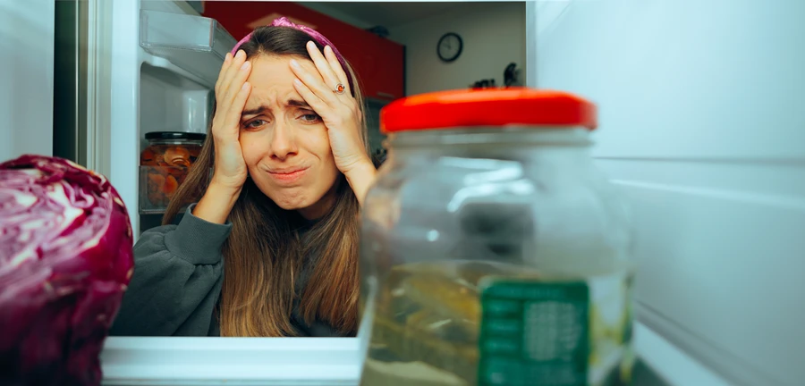 Image of homeowner discovering that her fridge won't cool.