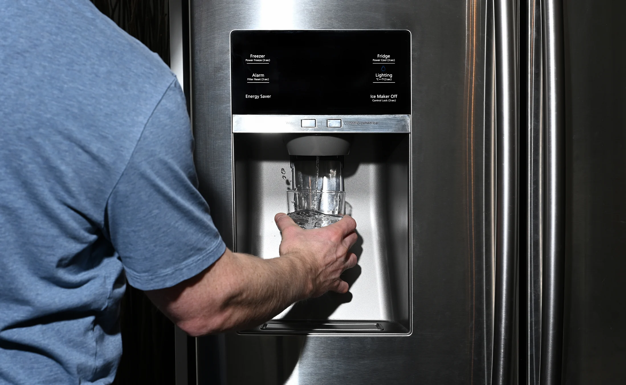 Homeowner dispensing water through a refrigerator carbon water filter and wondering "How Does Carbon Filtration Work?"